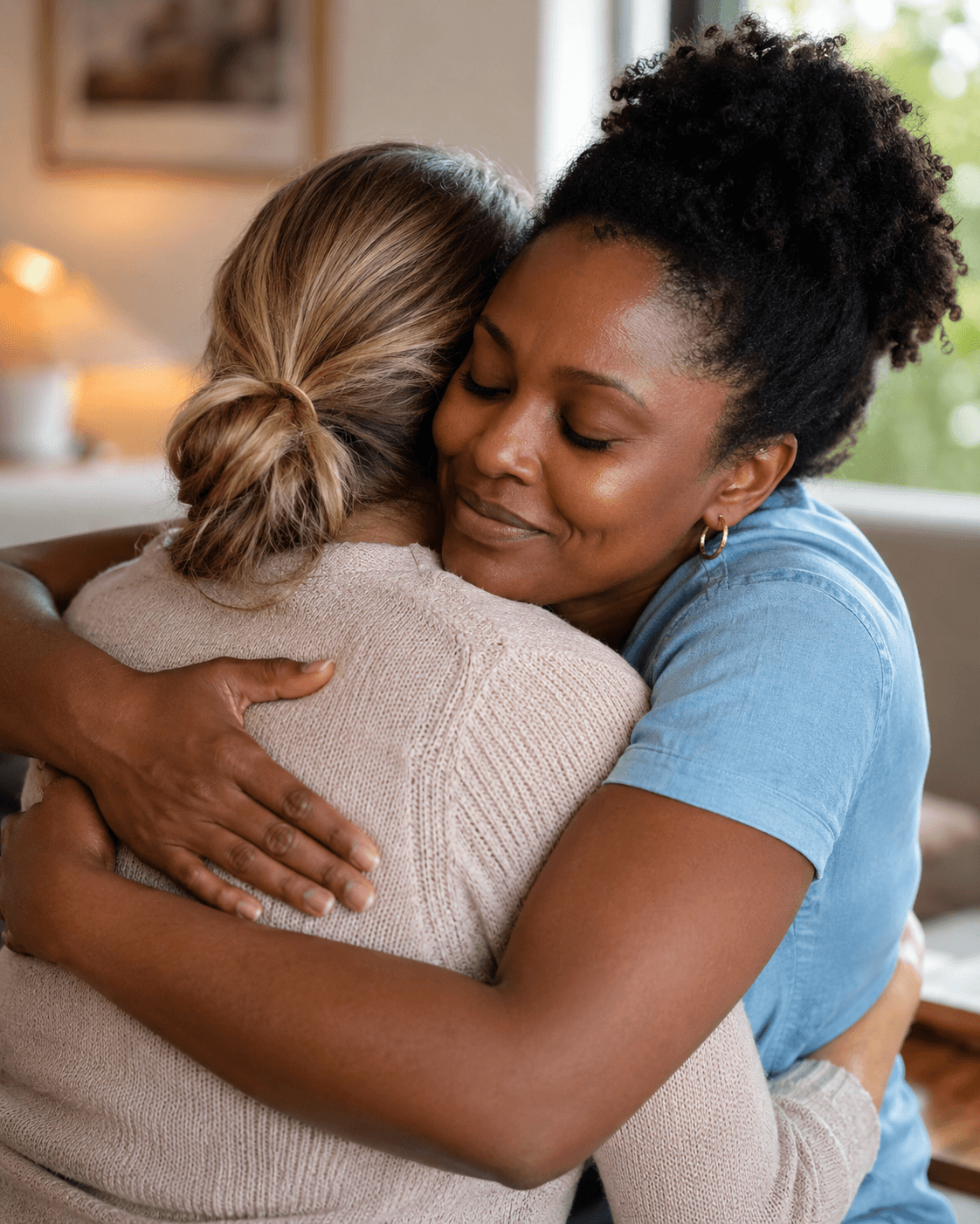 Two women embracing in a quiet home setting.